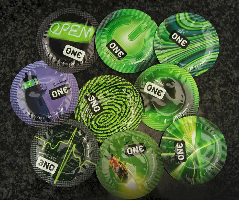 Nine individually wrapped ONE brand condoms with various designs and text.