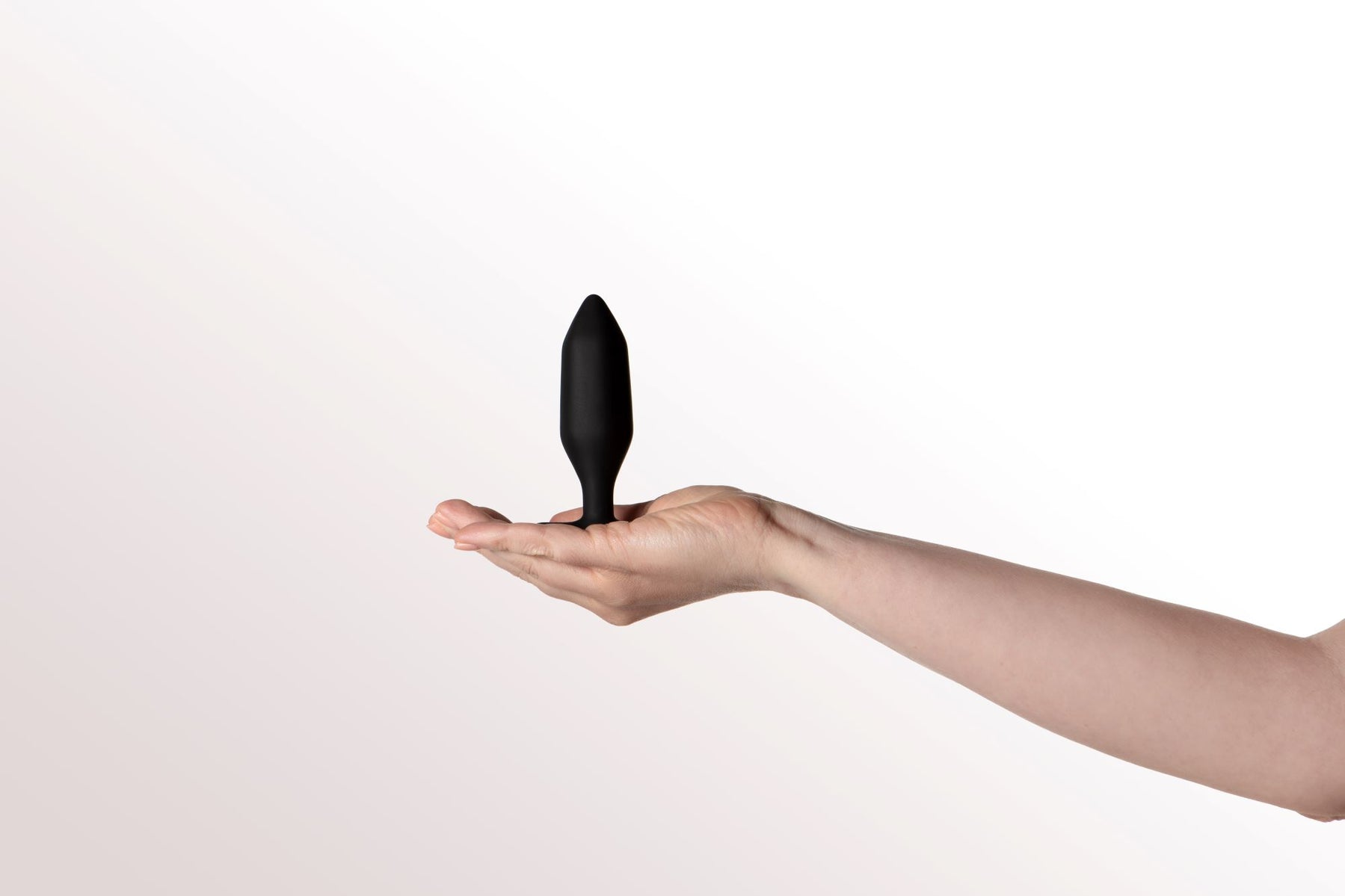 A black vibrating anal plug rests on an open palm.