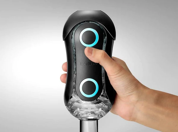 A hand holds a black Tenga Flip Orb Strong Blue Rush stroker with illuminated blue rings.