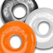 Three stretchy cock rings in orange, gray, and white, each with "ATOMIC-JOCK" embossed.