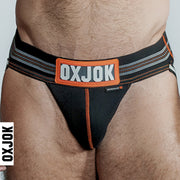 Black jockstrap with orange and white striped waistband and "OXJOK" logo.