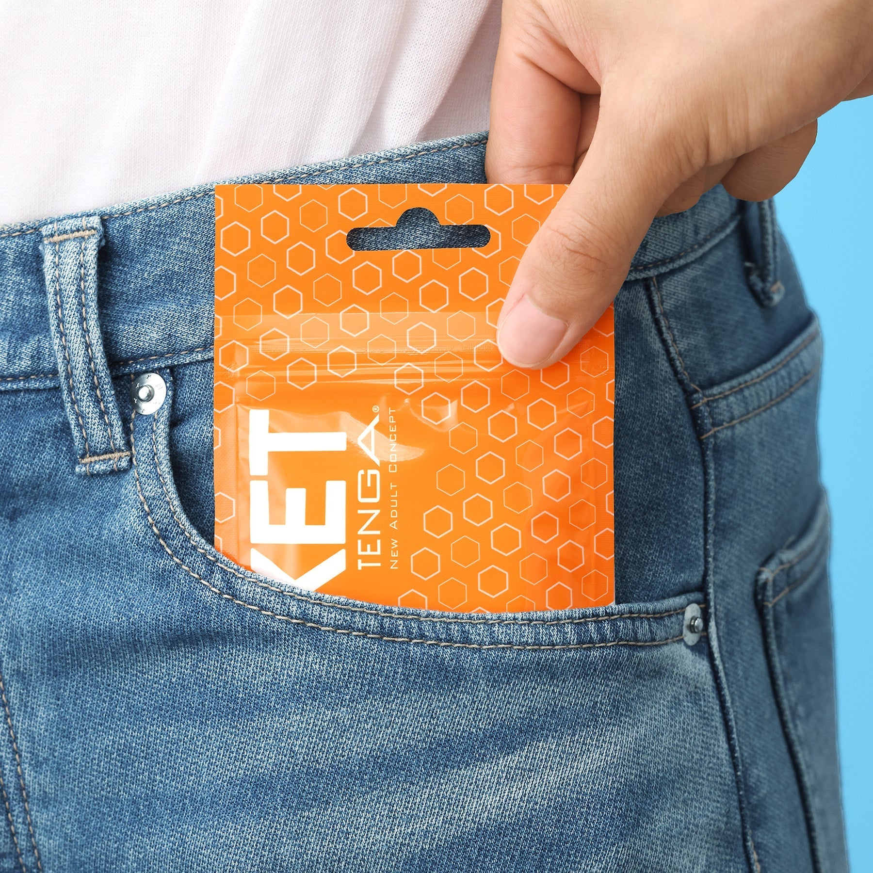A hand places a Tenga Block Edge disposable male masturbation sleeve into a denim pocket.