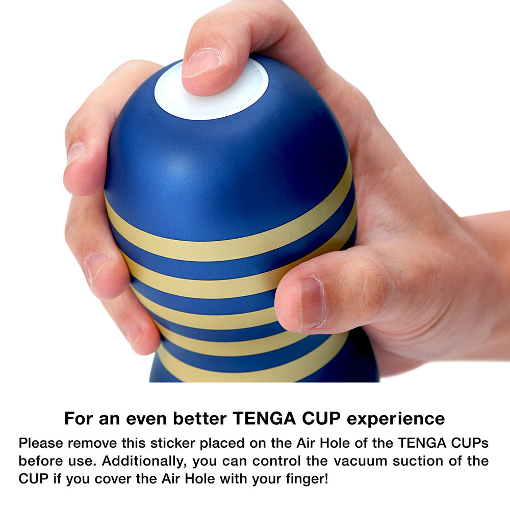 A hand holds a blue and gold striped Tenga vacuum cup.