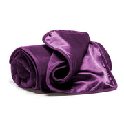 A rolled aubergine waterproof microvelvet throw blanket with a satin trim.