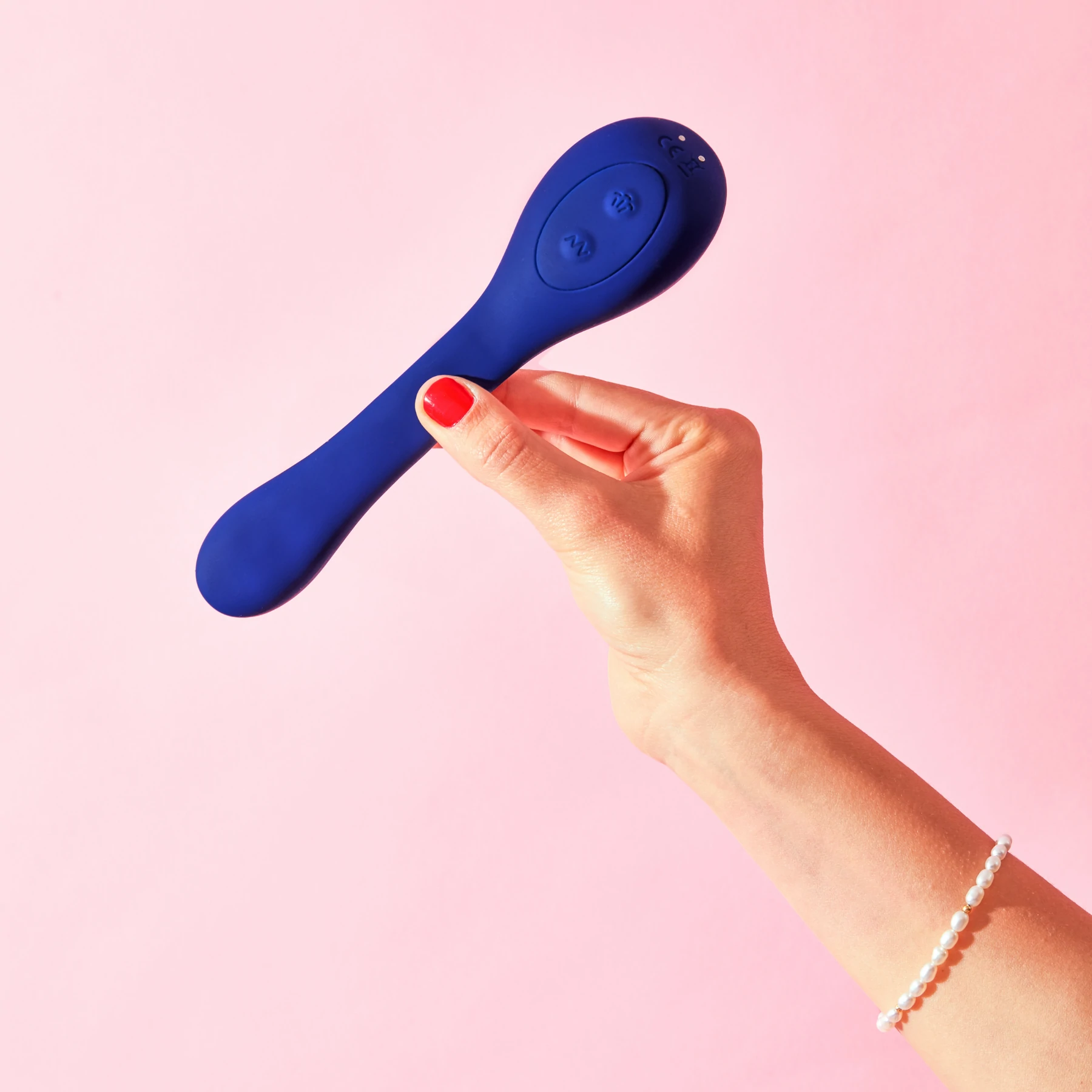 Blue silicone vibrator with two buttons held by a hand with red nail polish.
