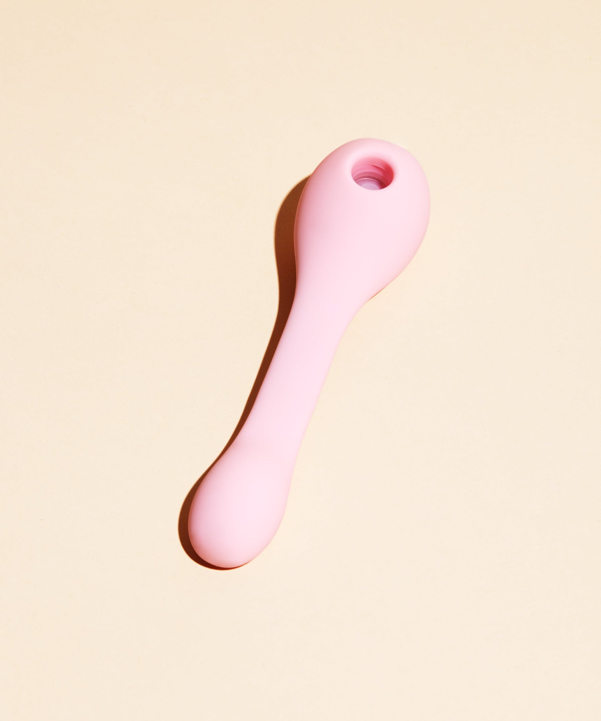 Pink dual stimulation suction vibrator with a hole at the top.