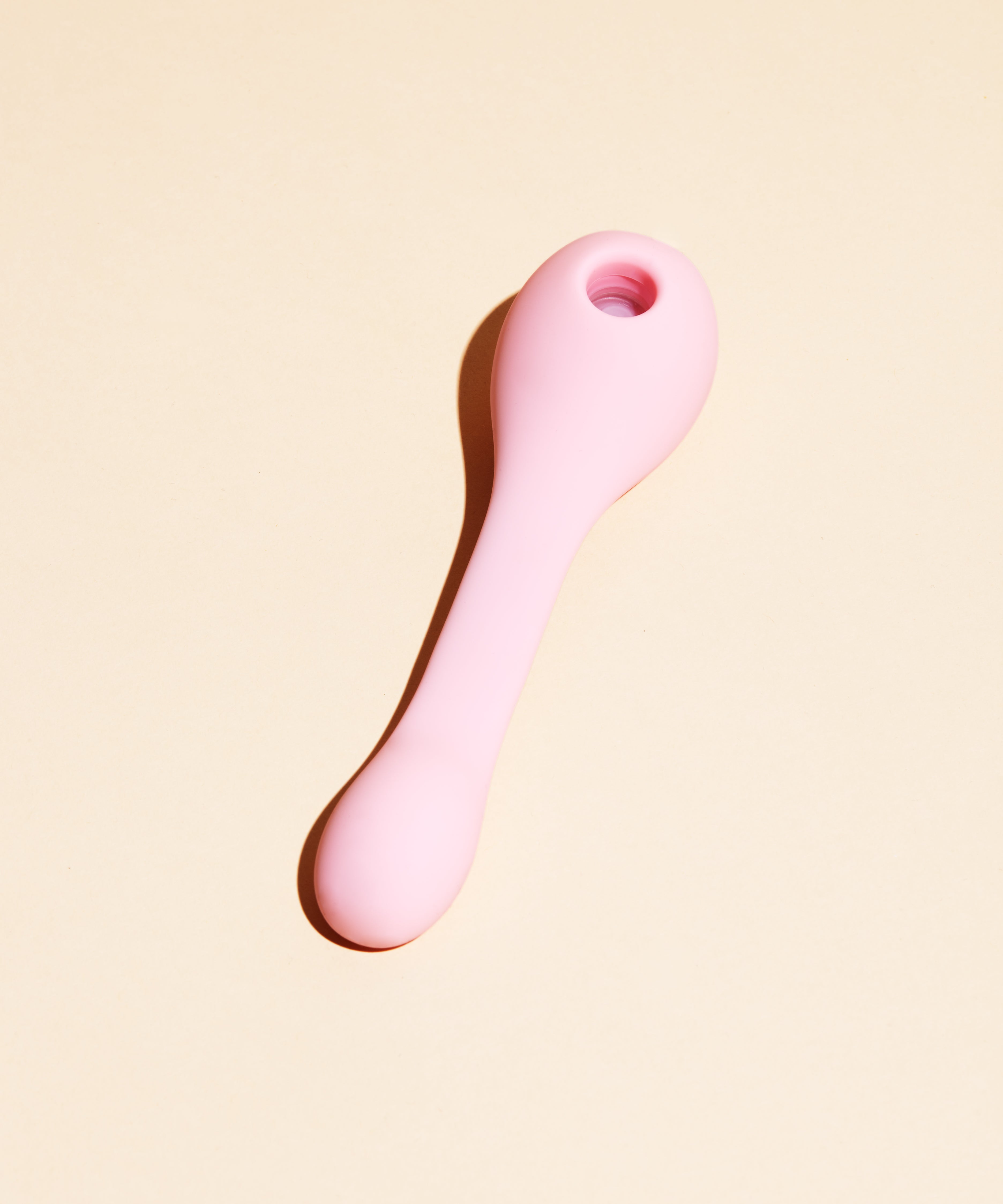 Pink dual stimulation suction vibrator with a hole at the top.