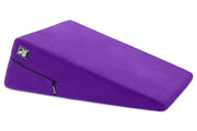 A purple wedge-shaped positioning pillow with a microfiber cover and a zipper.