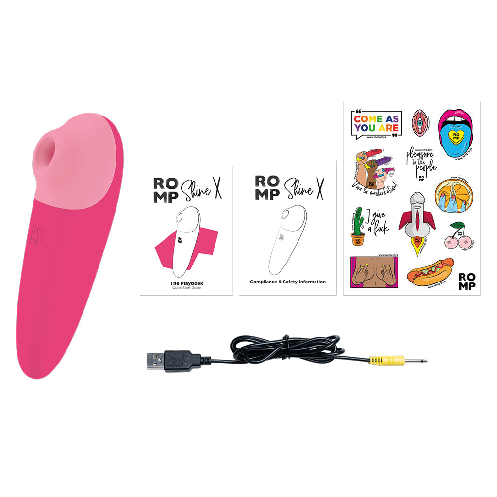 Pink and purple clitoral stimulator with charging cable and product literature.