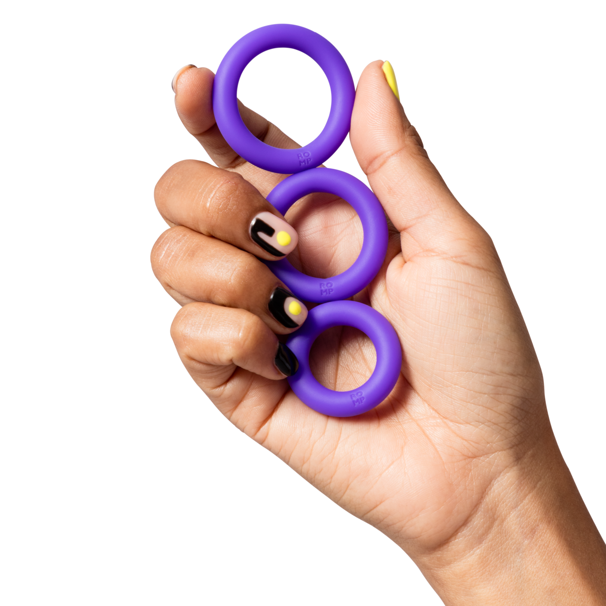 A hand holds three purple silicone rings with "ROMP" embossed on them.