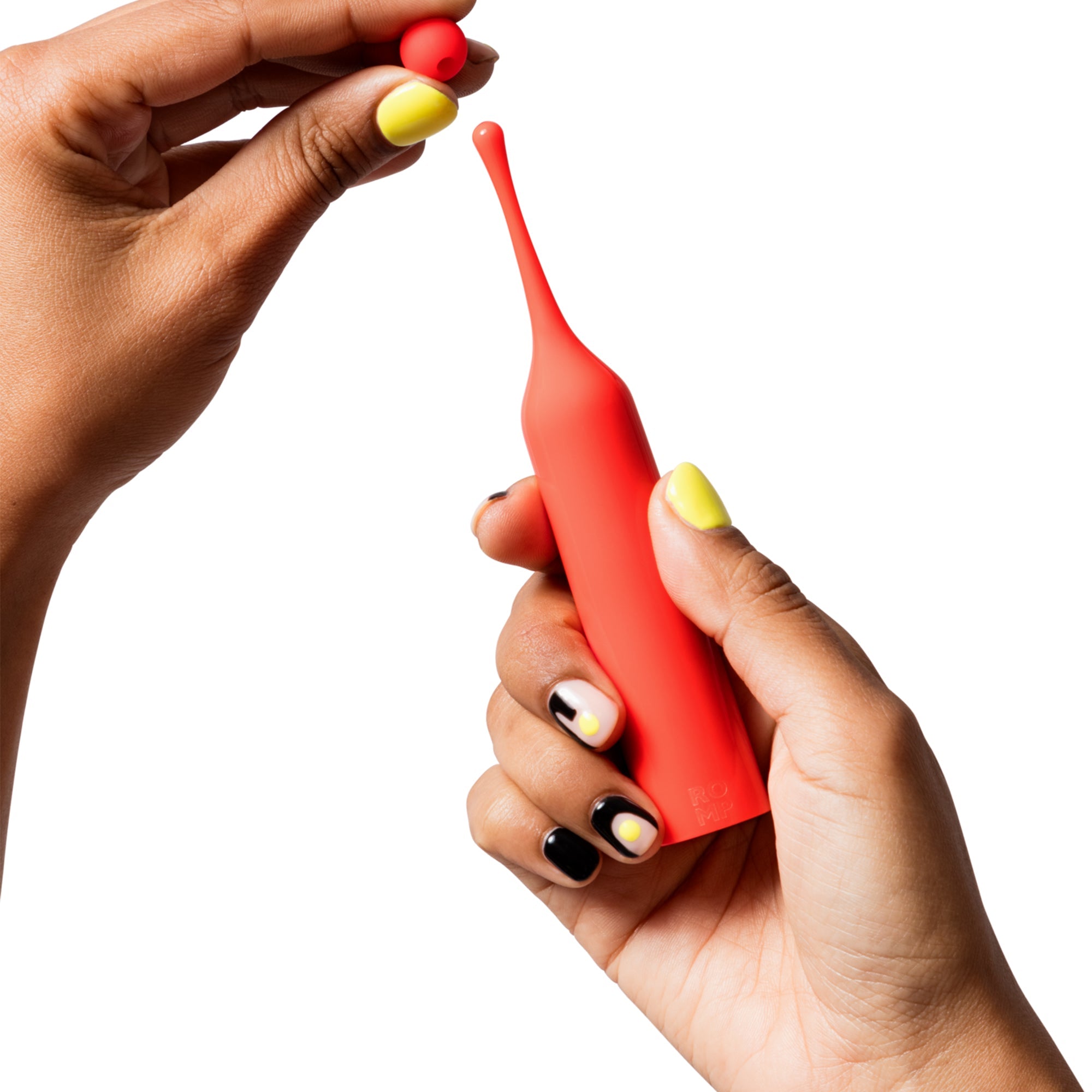 A red clitoral stimulator with two interchangeable heads is held by hands with colorful nail art.