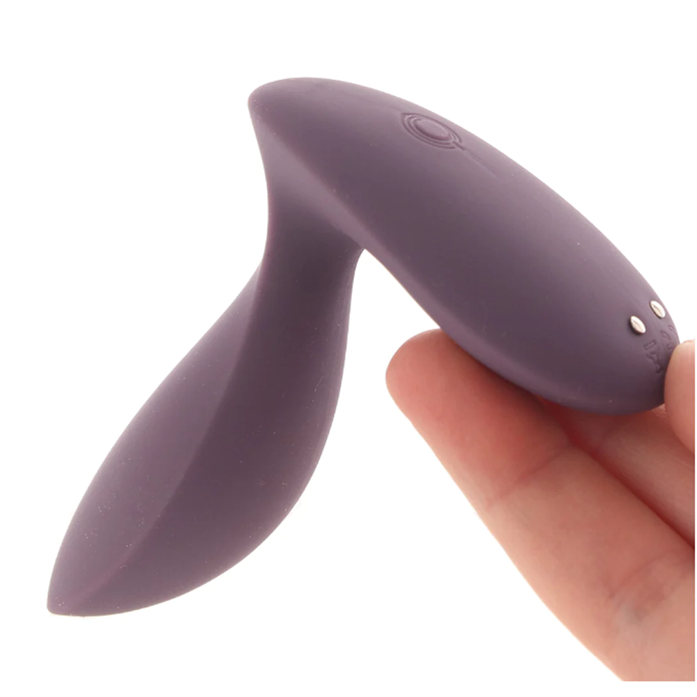 A purple silicone app-controlled vibrating anal plug held by a finger.