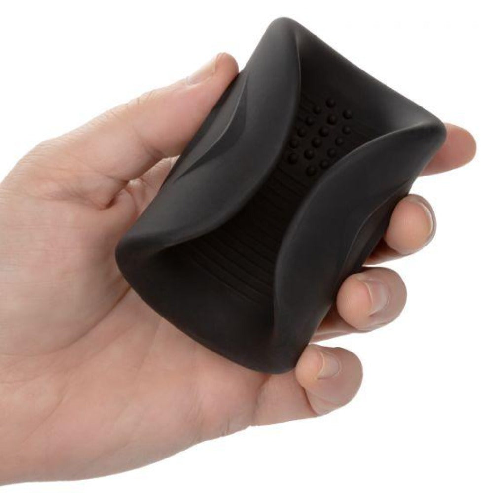 Black vibrating male masturbator with ribbed interior held in a hand.