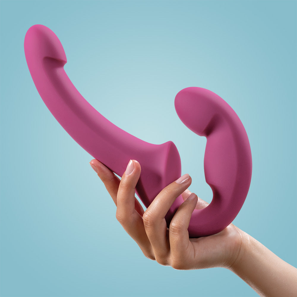 A pink double-ended G-spot dildo held in a hand.