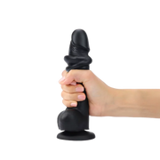 A hand holds a black realistic silicone dildo with veined texture and suction base.