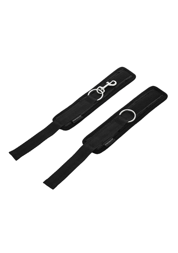 Black wrist cuffs with metal rings and a snap hook closure.