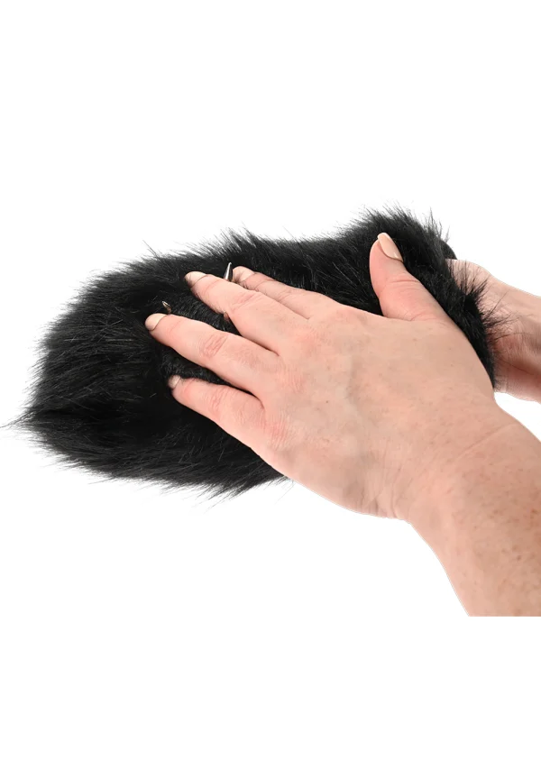 Black faux fur sensory mitt with hidden spikes being held by two hands.