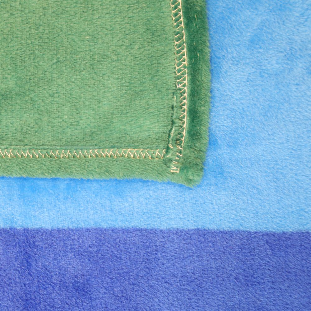 A green fleece blanket with white stitching is folded over a blue and purple striped blanket.