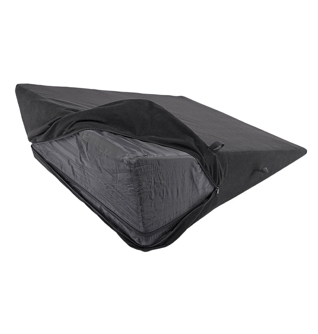 A black foam wedge pillow with a partially unzipped cover, revealing a dark interior.