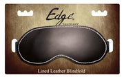 Black lined leather blindfold with white stitching on a textured background.
