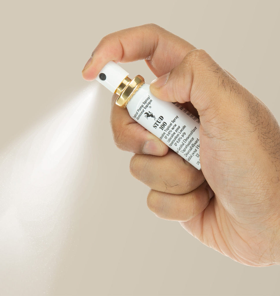 A hand sprays Stud 100 delay spray with 9.6% lidocaine.