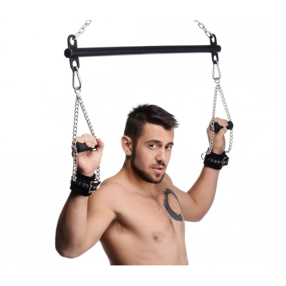 Man holding suspension bar handles with wrist restraints.