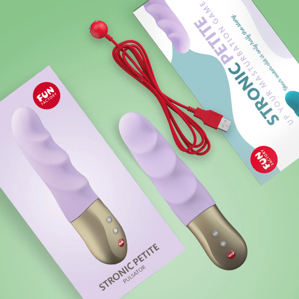 Two purple and gold Stronic Petite vibrators with charging cables on a green background.