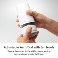 Hands adjust a white Tenga masturbator with a dial.