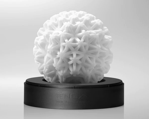 A white, geometric sphere-shaped masturbator sits on a black base.