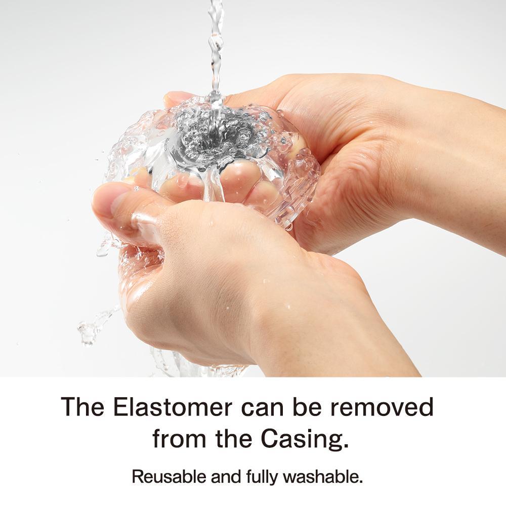 Hands washing a clear, textured masturbator under running water.