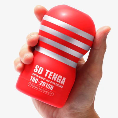A red Tenga Original Vacuum Cup with silver stripes held in a hand.
