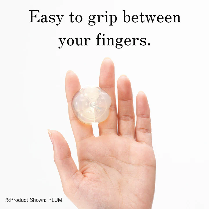 A hand holds a clear, flower-shaped pleasure item between two fingers.