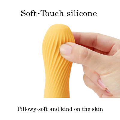 A hand squeezes a soft, ribbed, orange silicone vibrator.