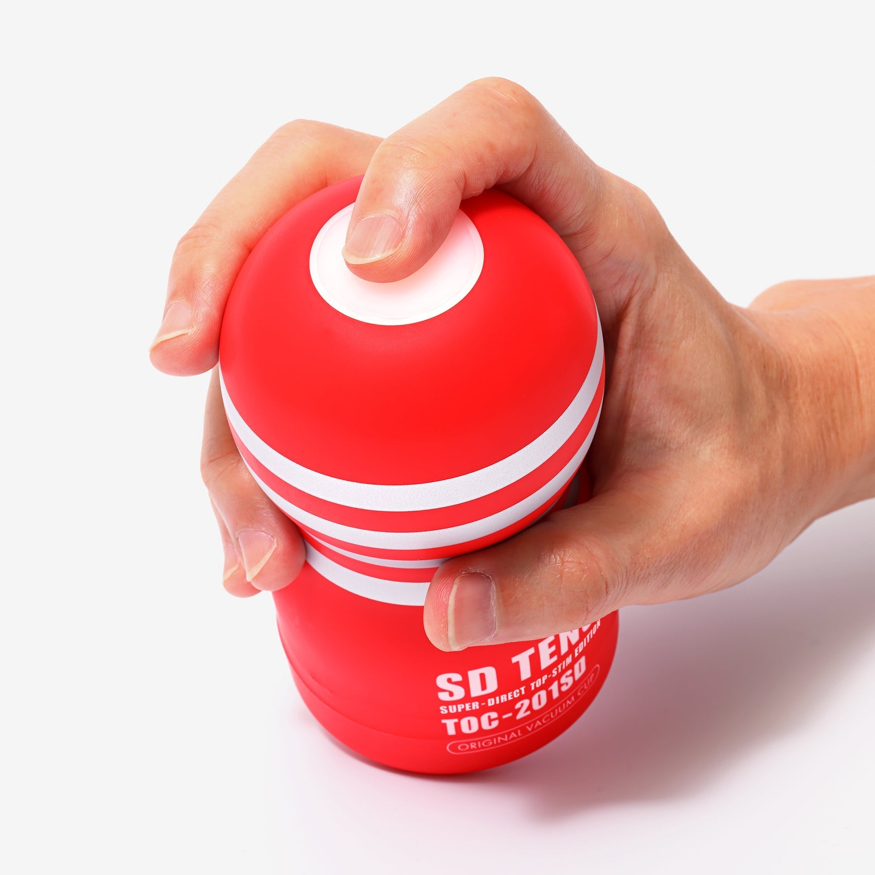 A hand holds a red and white striped Tenga vacuum cup masturbator.