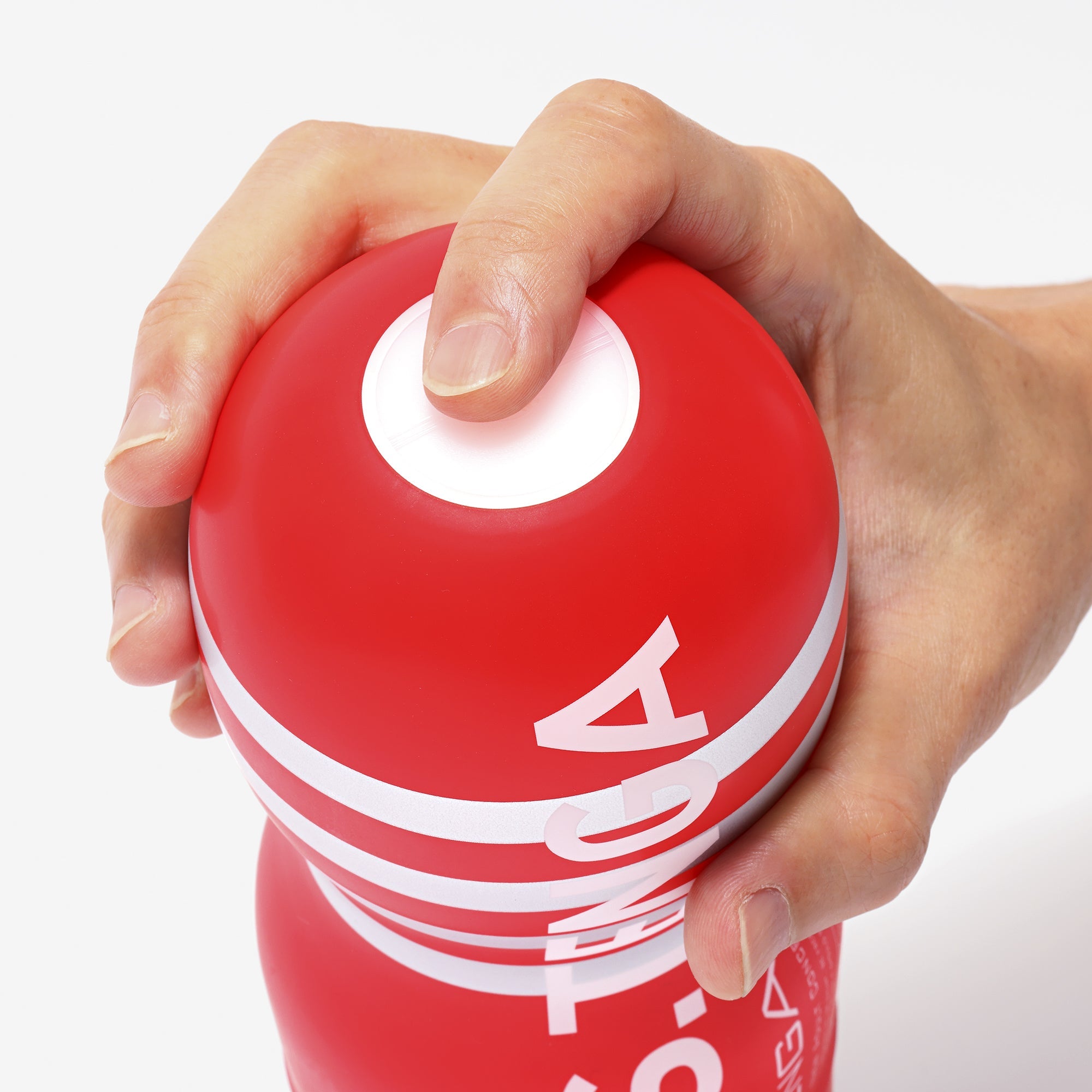 A hand holds a red Tenga Ultra Size Original Vacuum Cup with white stripes.