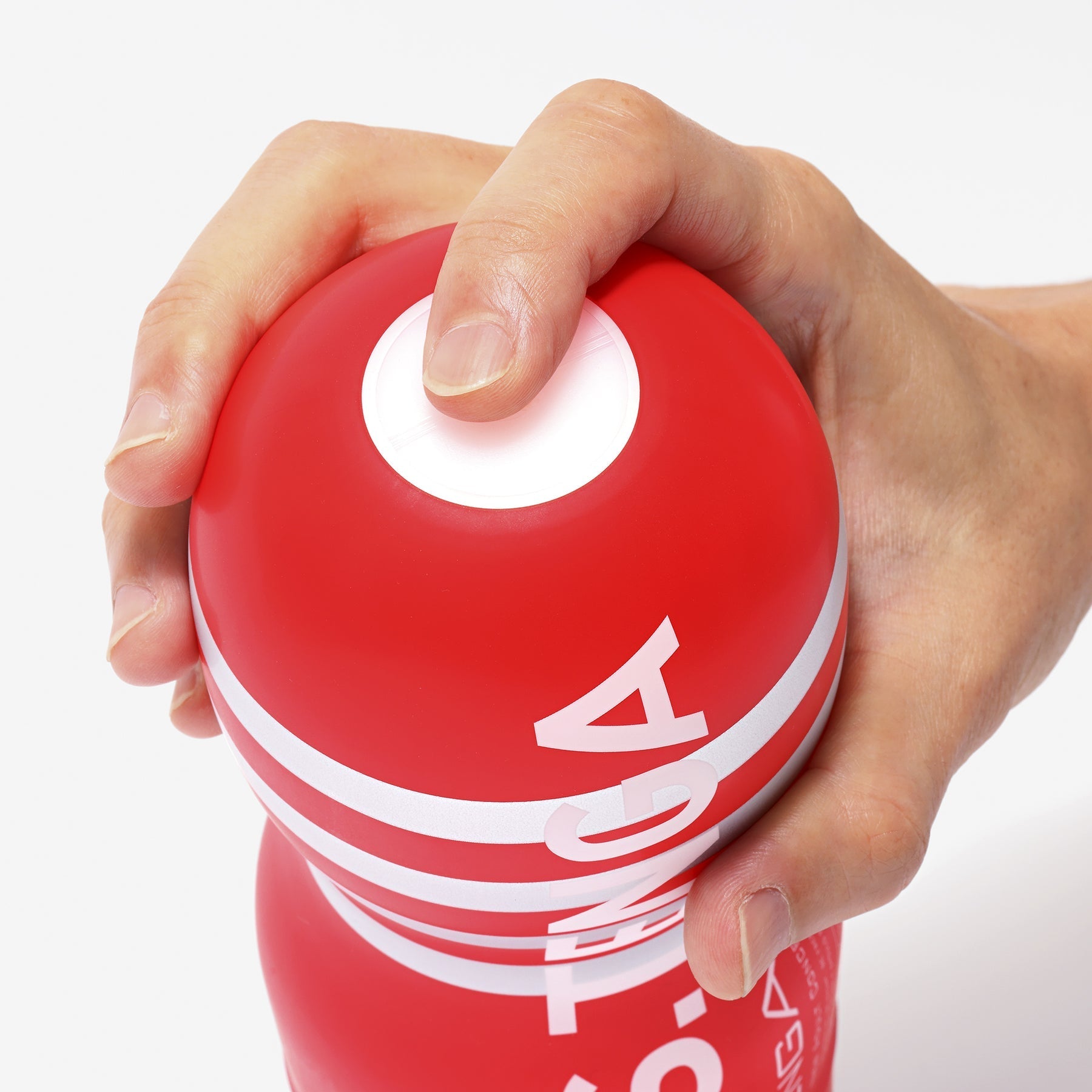 A red Tenga masturbator with white stripes and lettering, held by a hand.