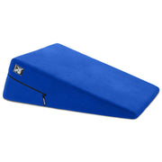 A blue wedge-shaped positioning pillow with a zipper and a logo.
