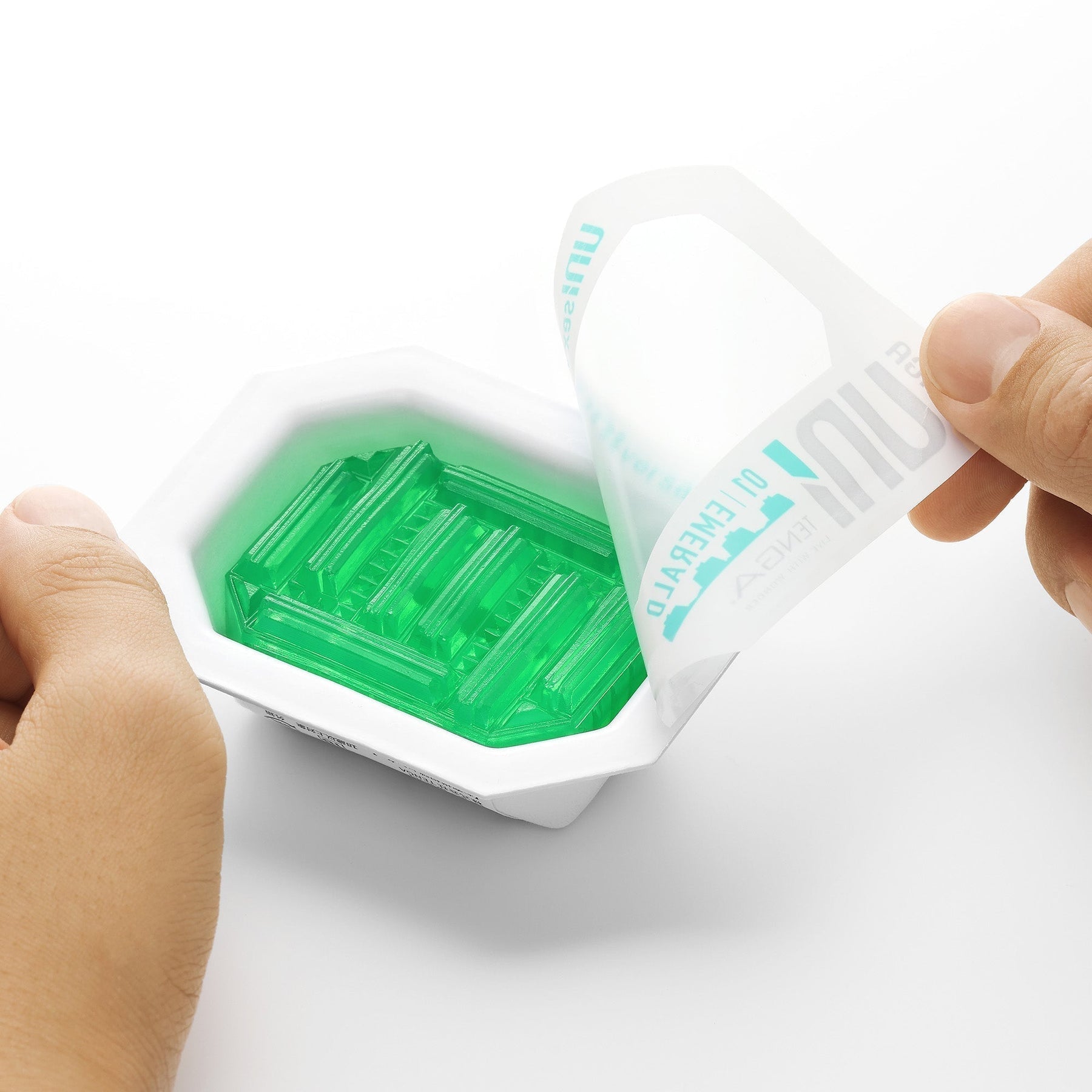 A hand peels open a package revealing green pleasure sleeves.