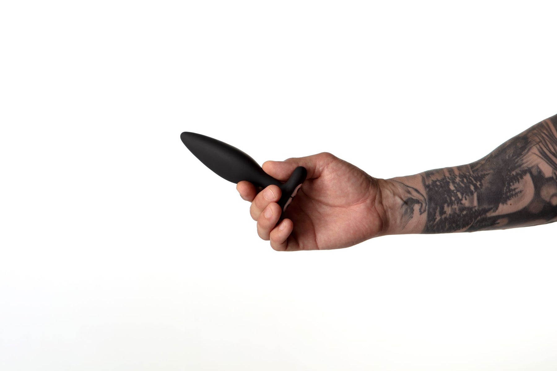 Black silicone vibrating butt plug held in a tattooed hand.