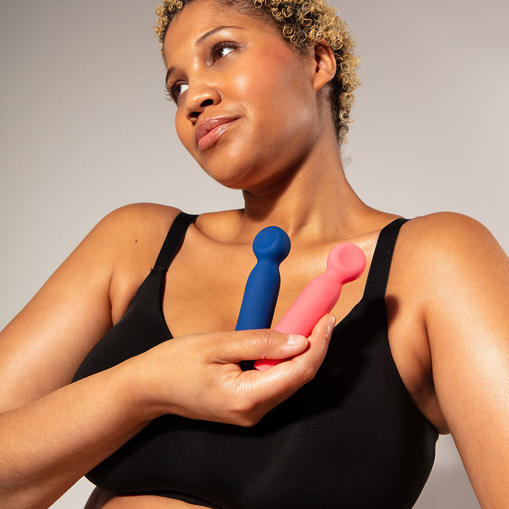 A woman holds a blue and pink vibrating bullet wand.