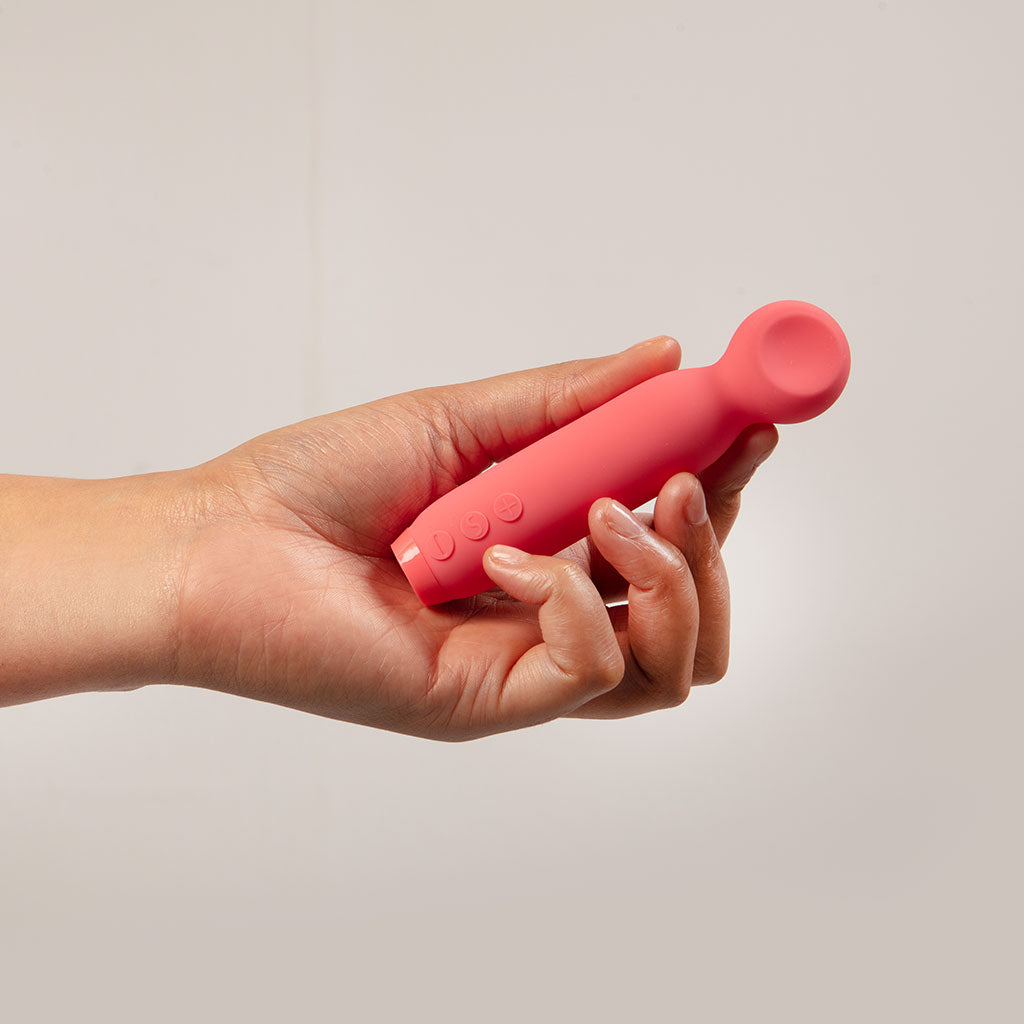 Pink wand tipped bullet vibrator with three buttons held in a hand.