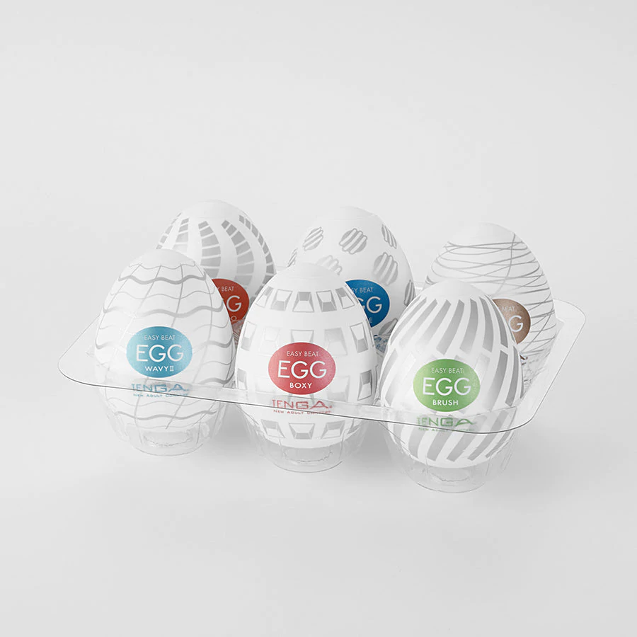 Six Tenga Egg masturbators in a clear plastic holder, each with a unique textured pattern.