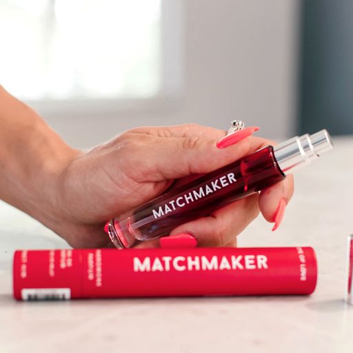 A hand holds a red perfume bottle labeled "MATCHMAKER" with a red tube below.