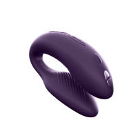 Purple couples vibrator with a curved shape and textured inner surface.
