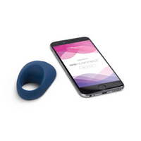 A blue silicone vibrating cock ring next to a smartphone displaying the We-Connect app.