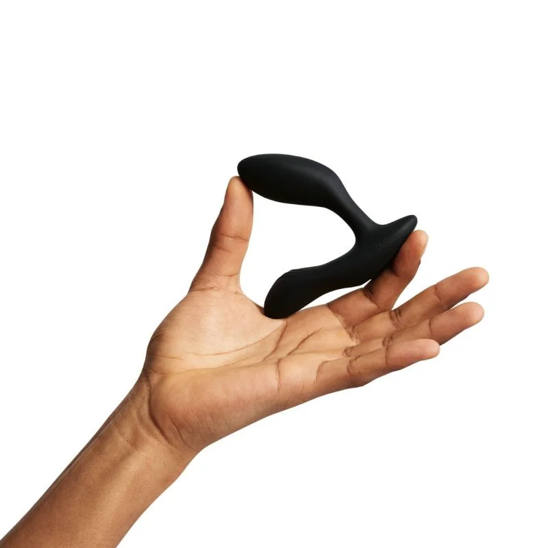 A black dual stimulation vibrator held in a hand.