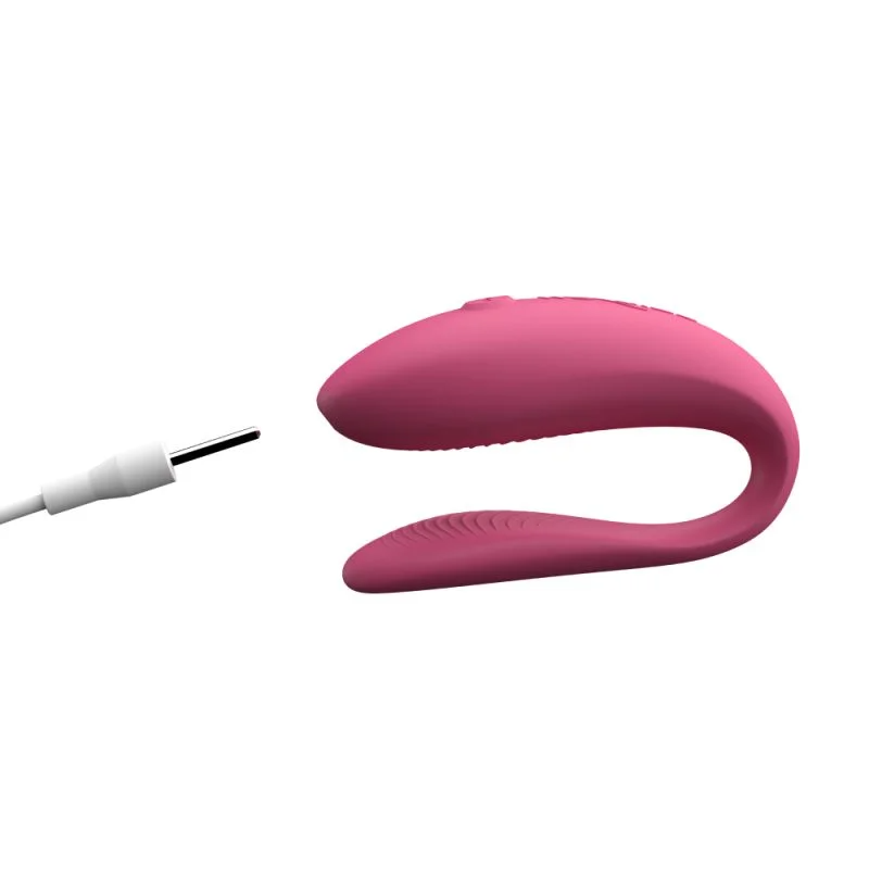 Pink app-controlled couples vibrator with charging cable.