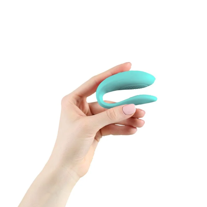 A hand holds a teal app-controlled couples vibrator.