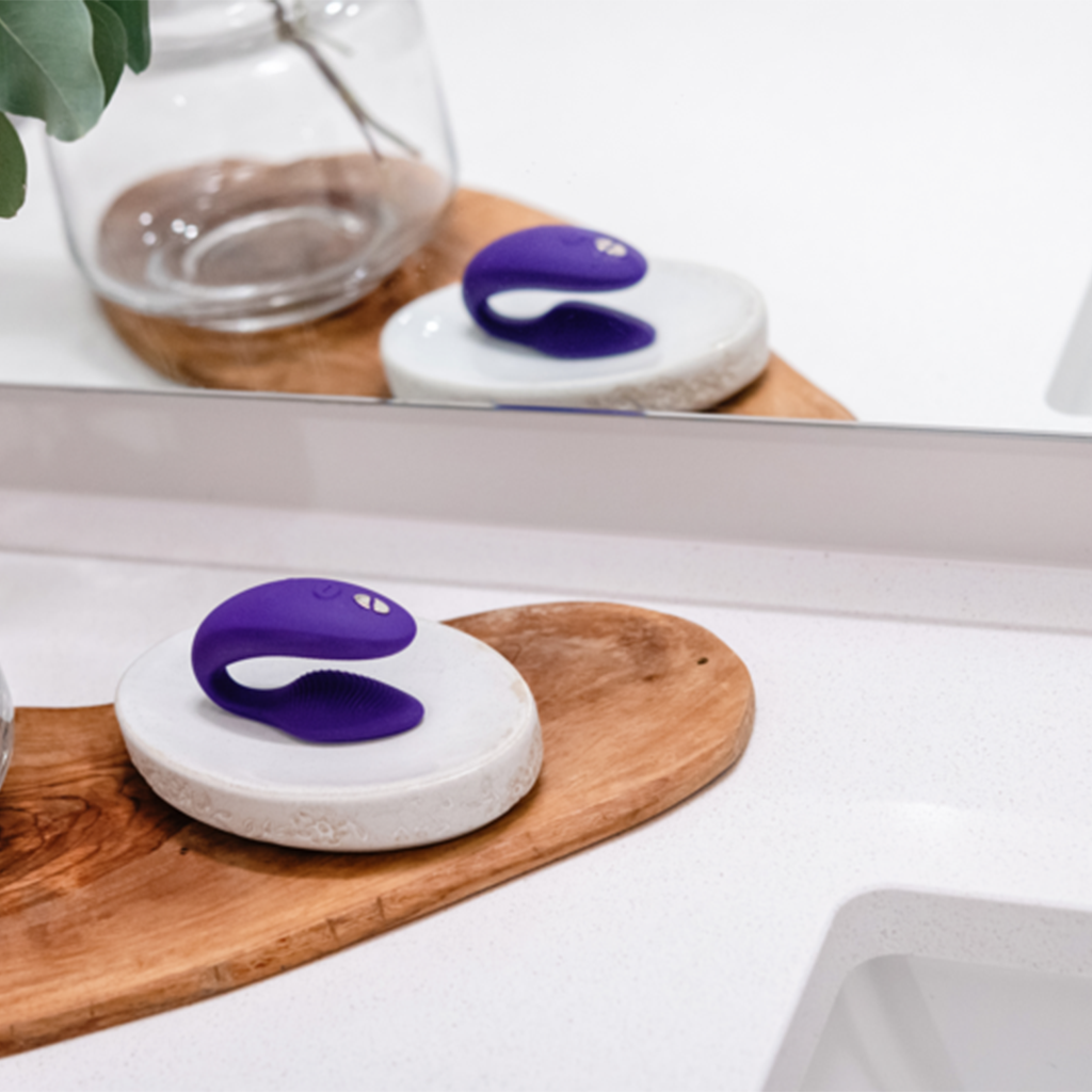 Purple Sync 2 couples vibrator on a white stone and wooden base.