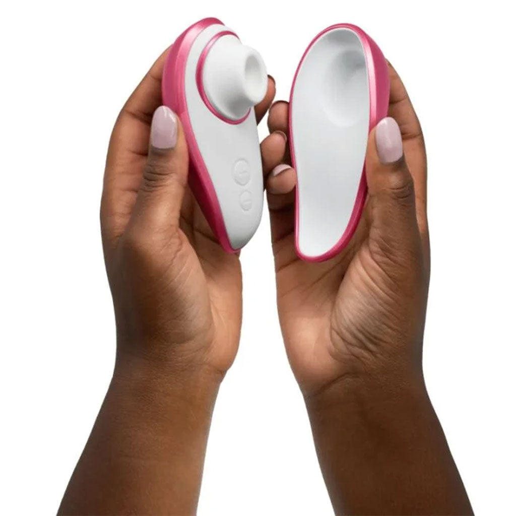 Pink and white Womanizer Liberty clitoral stimulator held in two hands.
